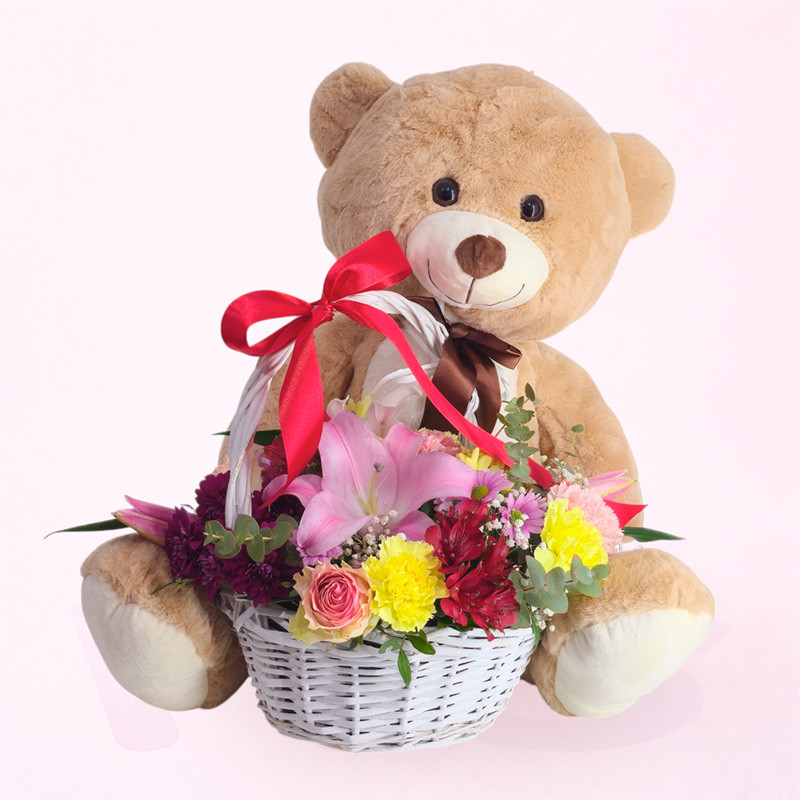 Cesta de flores con oso de peluche y combinación de rosas, claveles, margaritas y astromelias